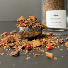 Loose leaf Rooibos tea piled high in a measuring spoon with the display jar of the same tea displayed in the background